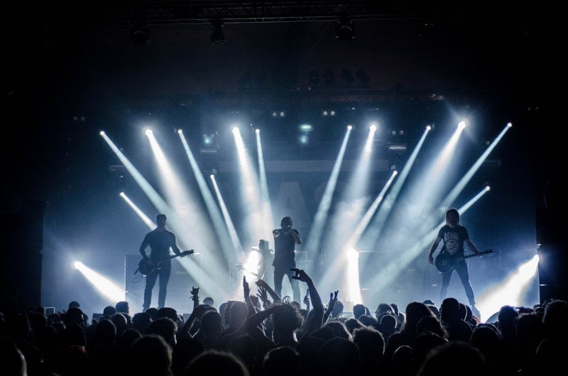 A band plays on stage, using Tap to surprise their audience with lights and other effects
